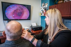 Carrie Rector checks a patient's ear canal with a video camera